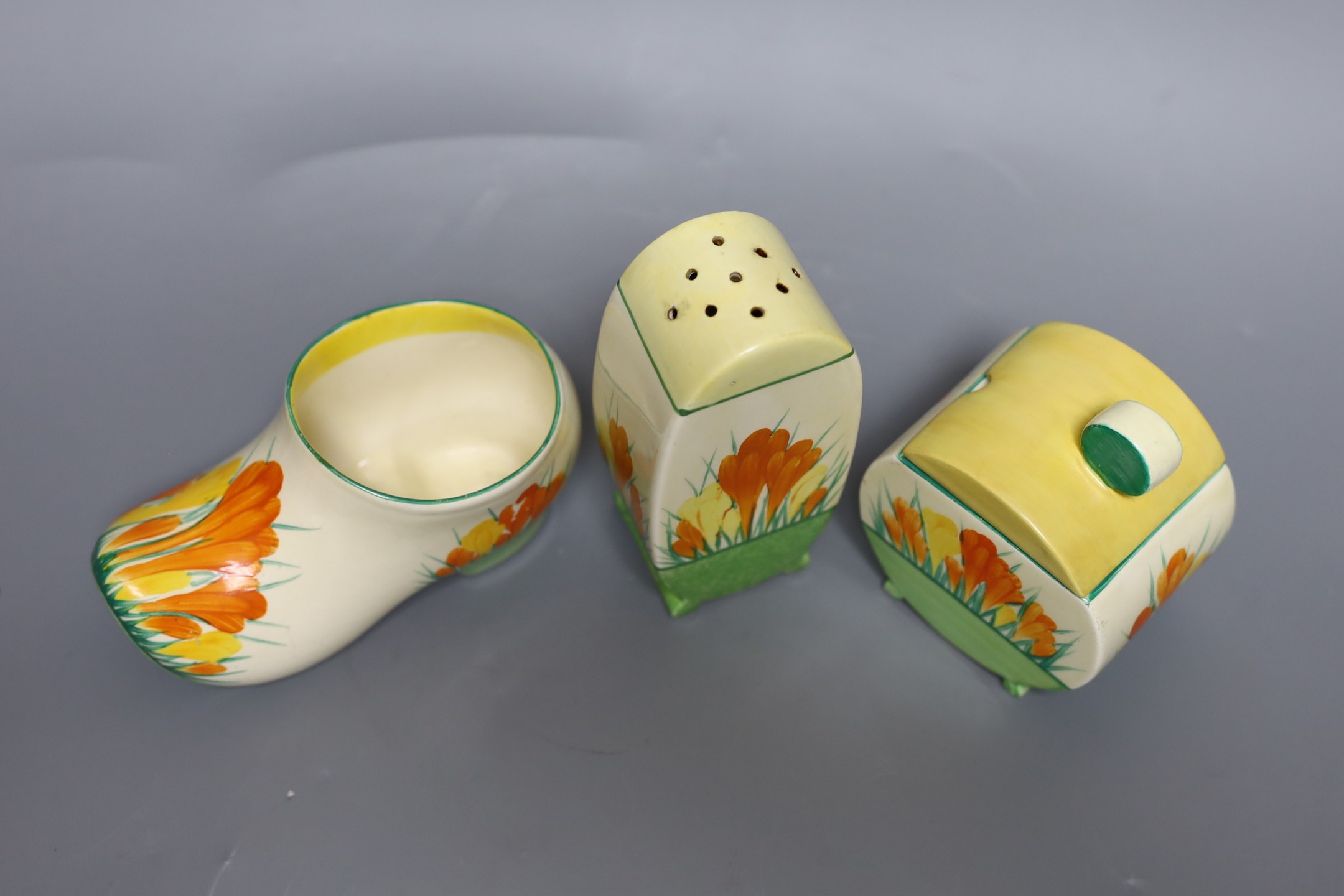 A Clarice Cliff sungleam crocus jam pot and cover, a sugar shaker and a Dutch clog ornament (3), jam pot and cover 10 cms high